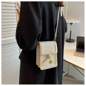 Detail of beige monogram crossbody bag with leather strap and gold pendant on model