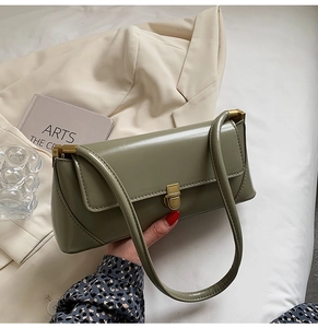 Close-up of retro green leather baguette bag with golden metal buckle and shoulder strap