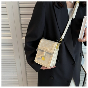 Detail of cream crossbody bag with letter print patterns and golden tassel charm