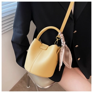 Détail du sac seau en cuir grainé jaune avec foulard imprimé et boucles dorées