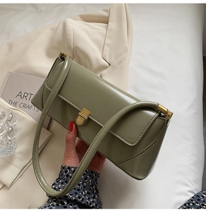 Detail of vintage sage green baguette bag with glossy texture and gold square metal lock