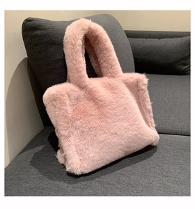 Close-up of soft pink faux fur tote bag texture on a modern gray fabric sofa
