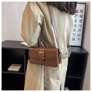 Brown vintage faux leather crossbody bag styled with a beige trench coat for a chic look