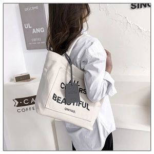 Detail of off-white canvas tote bag featuring ALL COLORS ARE BEAUTIFUL graphic print