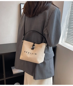 Detail of canvas bucket bag featuring leather trim, horn buckle, and shoulder strap