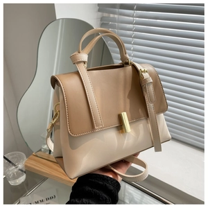 Détail d'un sac bandoulière bicolore avec ferrures dorées et poignées cylindriques