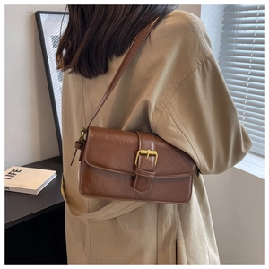Detailed shot of a vintage brown shoulder bag with golden buckle and sleek leather texture