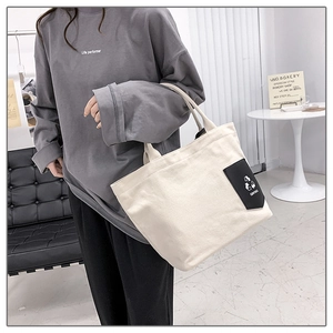 Close-up of a minimalist cream canvas tote bag showing textured fabric and black brand label
