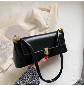 Detail of black matte leather shoulder bag with elegant gold metal buckle and dual straps