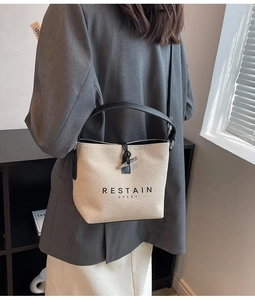 Detail of canvas bucket bag with leather trim and horn buckle worn by a model