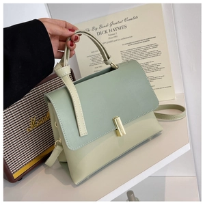 Détail du sac à main bicolore en cuir avec fermoir doré et bandoulière à nœud décoratif