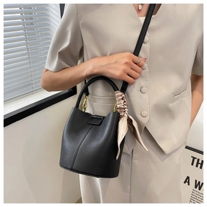 Détail du sac seau en cuir noir avec texture litchi et foulard en soie décoratif