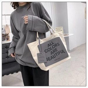 Detail of canvas tote bag showing 'ALL COLORS ARE BEAUTIFUL' print and grey patch detail