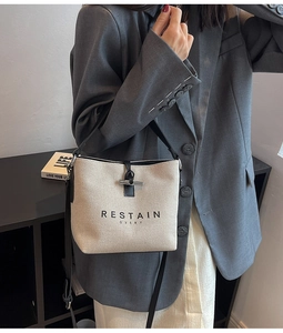 Detail of cream canvas bucket bag with black leather trim and horn buckle closure