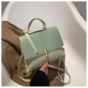 Détail du sac à bandoulière bicolore vert menthe avec boucle dorée sur une chaise