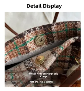 Close-up of golden magnetic snap closure on tweed plaid tote bag with brown leather strap