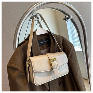 Detail of a chic cream white textured leather handbag on a brown blazer shoulder