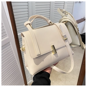 Détail d'un sac à main en cuir crème avec boucle dorée et bandoulière réglable via miroir