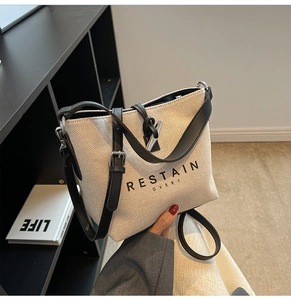 Detail of canvas bucket bag with black leather trim and silver metal hardware accents