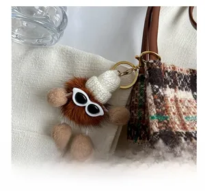 Detail show of a plush faux fur bear charm with knit hat and sunglasses on a tote bag