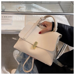 Détail d'un sac à main minimaliste en cuir blanc cassé avec fermoir doré dans un décor chic