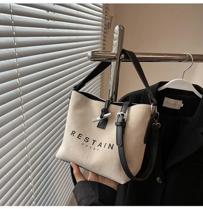 Detail of canvas bucket bag featuring black leather trim and silver horn buckle closure