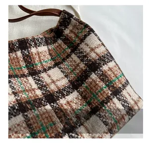 Detail view of woven tweed fabric in brown plaid with premium leather handle stitching