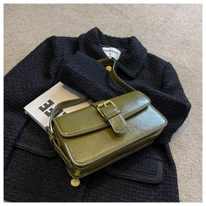 Close-up of olive green retro shoulder bag with glossy oil wax leather and gold buckle