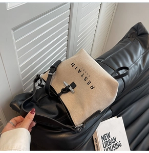 Detail of canvas bucket bag showing metal buckle closure and black leather strap