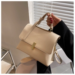 Détail d'un sac en cuir crème avec un fermoir rotatif métallique doré très élégant