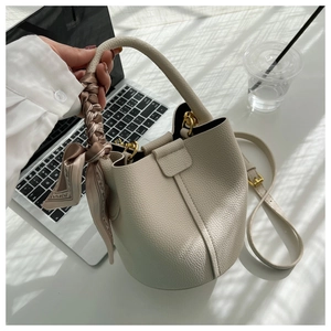 Détail du sac seau blanc cassé en cuir grainé avec foulard en soie sur la poignée