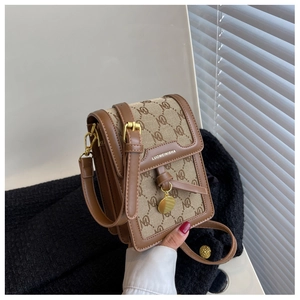Detailed view of canvas crossbody bag with leather trim and gold metal logo plaque