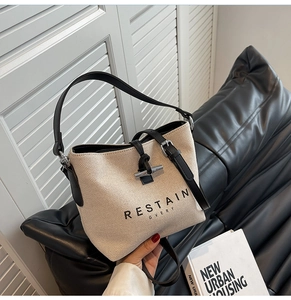 Detail of canvas bucket bag with black leather trim and metal horn toggle closure