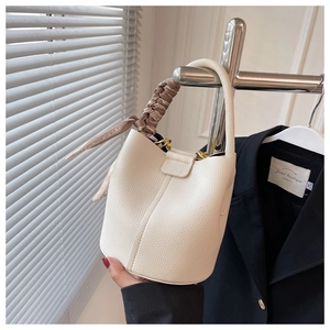 Détail du sac seau crème avec poignée enroulée d'un foulard en soie sur cintre