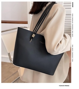 Detailed side view of a large black matte leather tote bag worn with a beige blazer