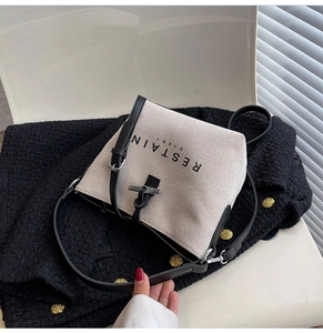 Detail of canvas bucket bag showing leather drawstring, metal buckle and logo print