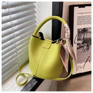 Détail du sac seau en cuir vert chartreuse avec foulard en soie sur la poignée