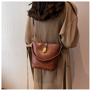 Detail of a dark brown vintage bucket bag with retro leather texture and golden buckle