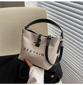 Close-up of canvas bucket bag with leather horn buckle and contrast lettering