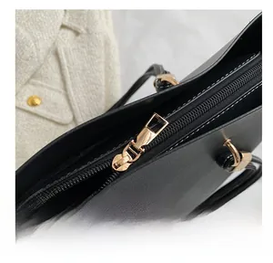 Detail shot of smooth gold-tone zipper and textured black leather on a commute tote bag