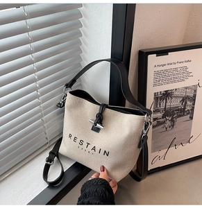 Close-up of canvas tote bag with black leather straps and silver metal toggle closure