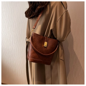 Brown vintage leather bucket bag featuring gold rotating lock and long shoulder strap