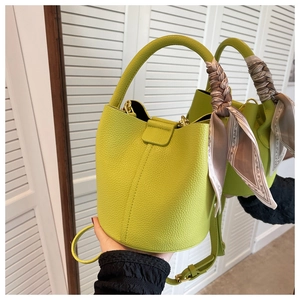 Gros plan du sac seau en cuir vert citron avec un foulard en soie noué sur la poignée