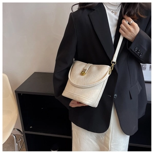 Close-up of creamy white bucket bag with wave-textured leather and gold metal buckle