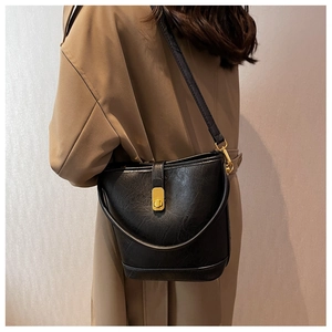 Detail view of a black bucket bag with cracked texture leather and gold metal clasp