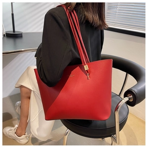 Close-up of red lychee grain leather tote bag with gold logo and shoulder straps