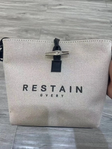 Close-up of beige canvas tote bag with bamboo toggle closure and premium leather trim