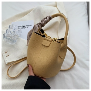 Détail du sac seau en cuir jaune avec foulard en soie sur la poignée et bandoulière