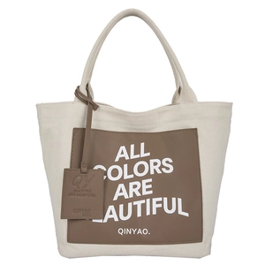 Minimalist cream canvas tote bag with dark brown leather pocket and white slogan print