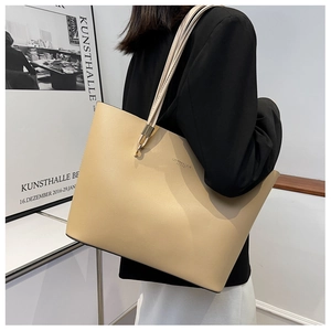 Elegant beige tote bag on model's shoulder showing large capacity and minimal design